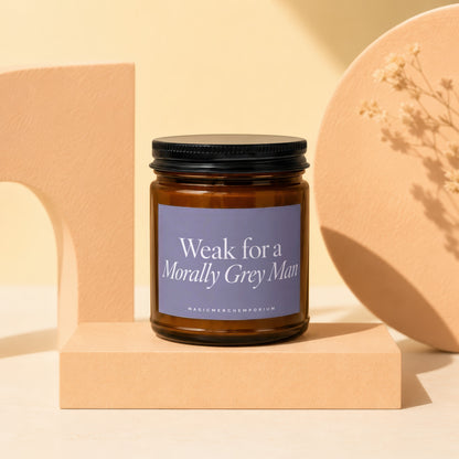 Amber glass candle with black lid, labeled "Weak for a Morally Grey Man."