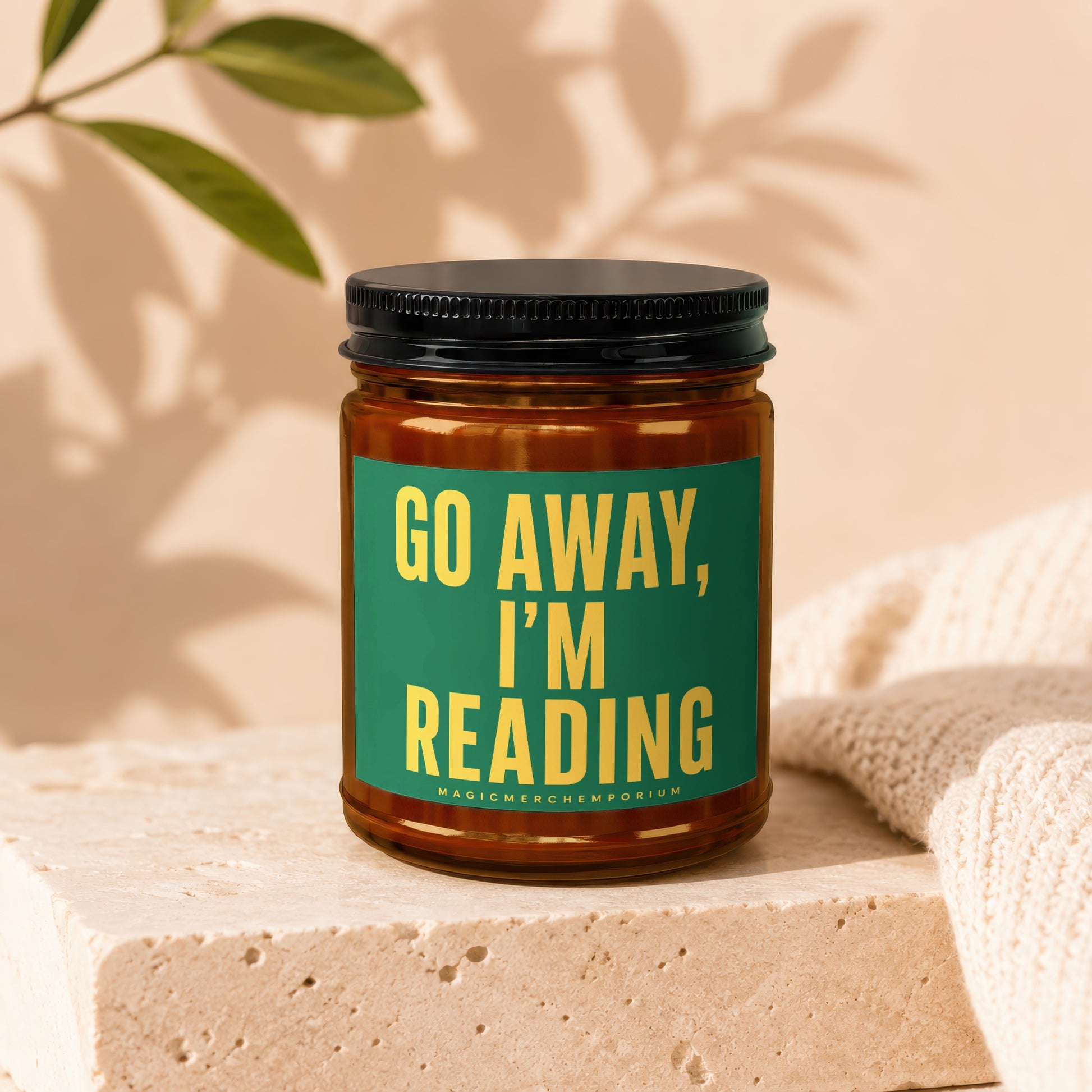 Amber jar candle with green label reading "GO AWAY, I'M READING".