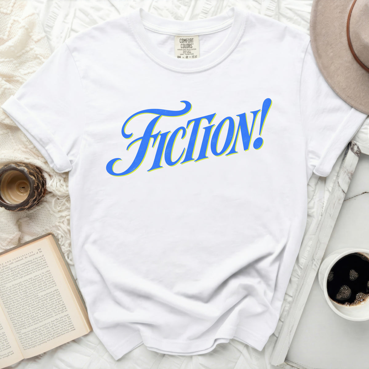 White t-shirt with blue and yellow "FICTION!" graphic and Comfort Colors tag.