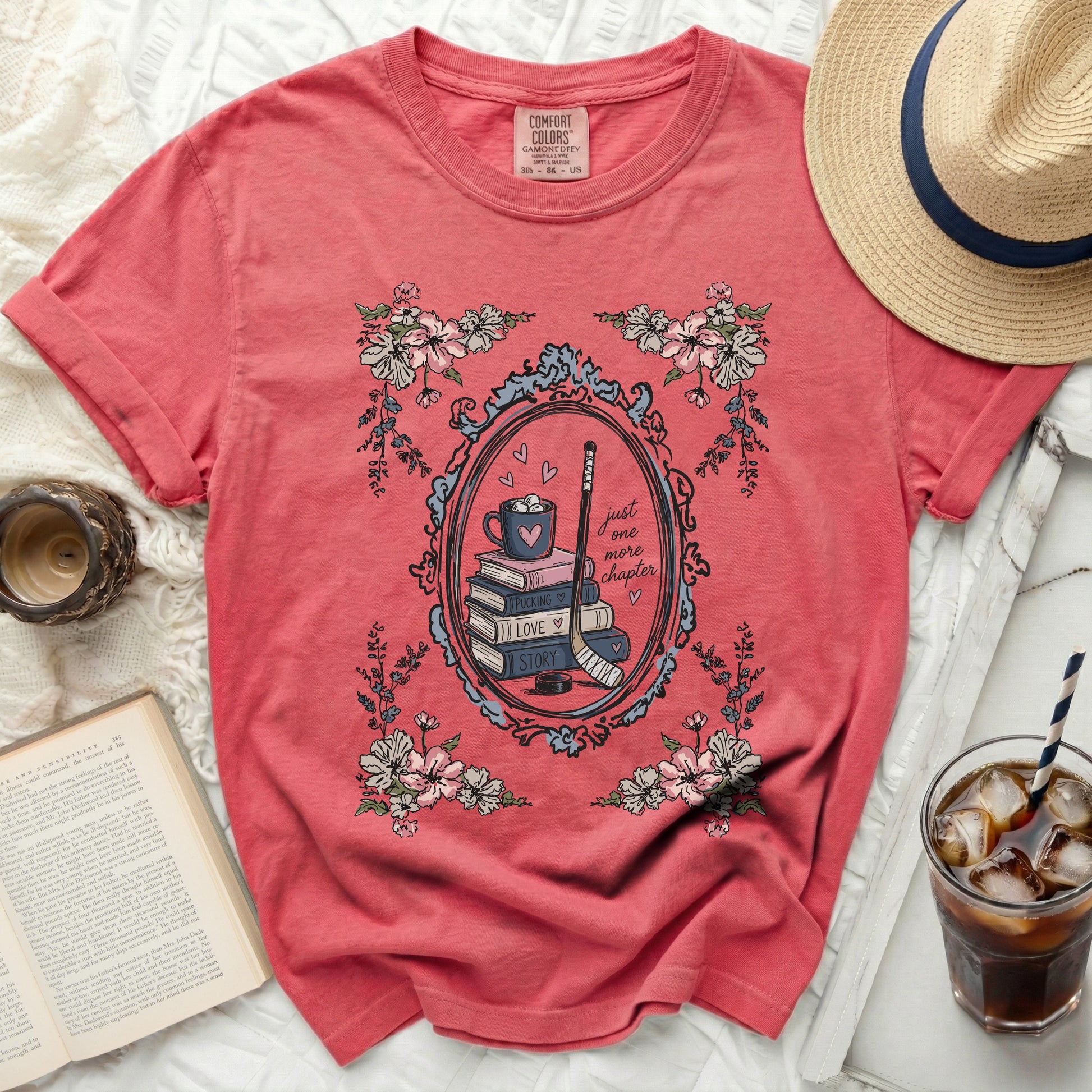 Coral t-shirt with oval frame of flowers and hockey gear, text "just one more chapter"