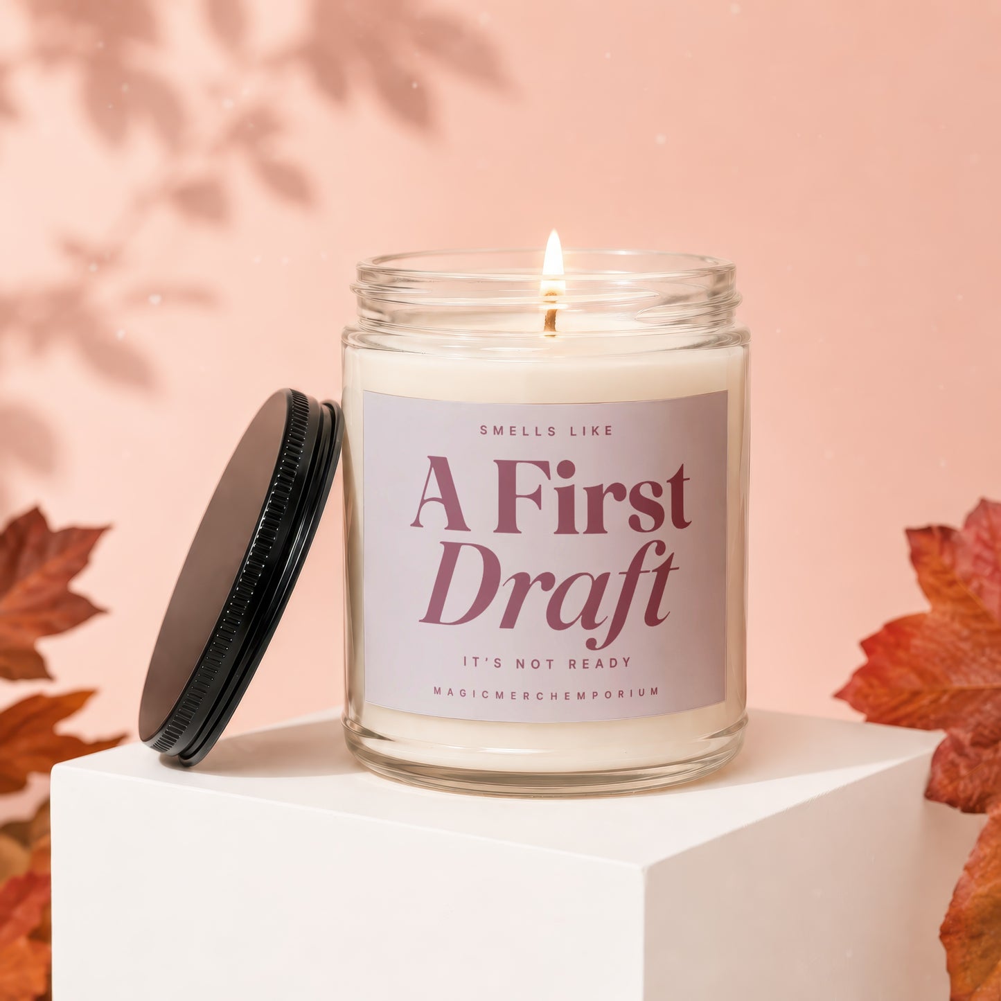 Lit candle in a jar with a label reading "Smells Like A First Draft It's Not Ready".