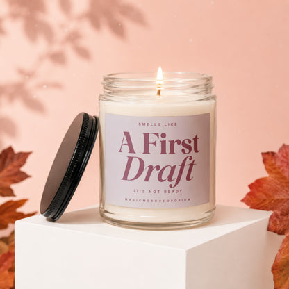 Lit candle in a jar with a label reading "Smells Like A First Draft It's Not Ready".