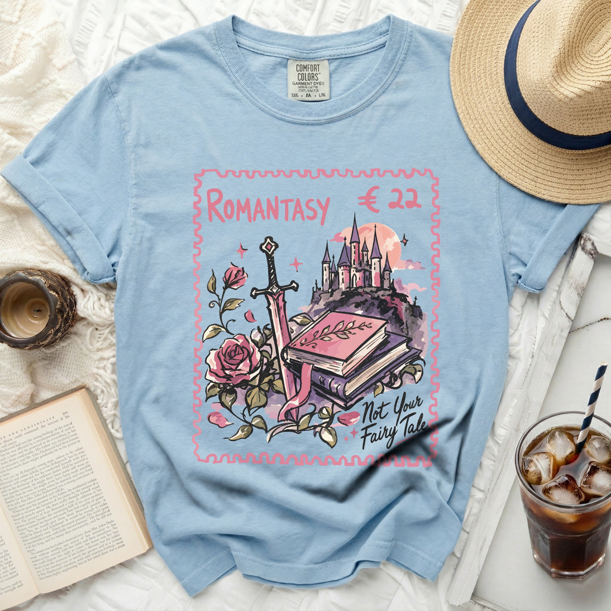 Light blue t-shirt with a stamp-shaped graphic featuring a castle, sword, roses, and text.