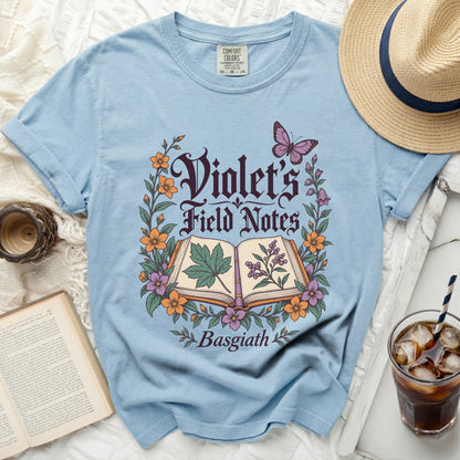 Light blue t-shirt with "Violet's Field Notes Basgiath" text and floral design.
