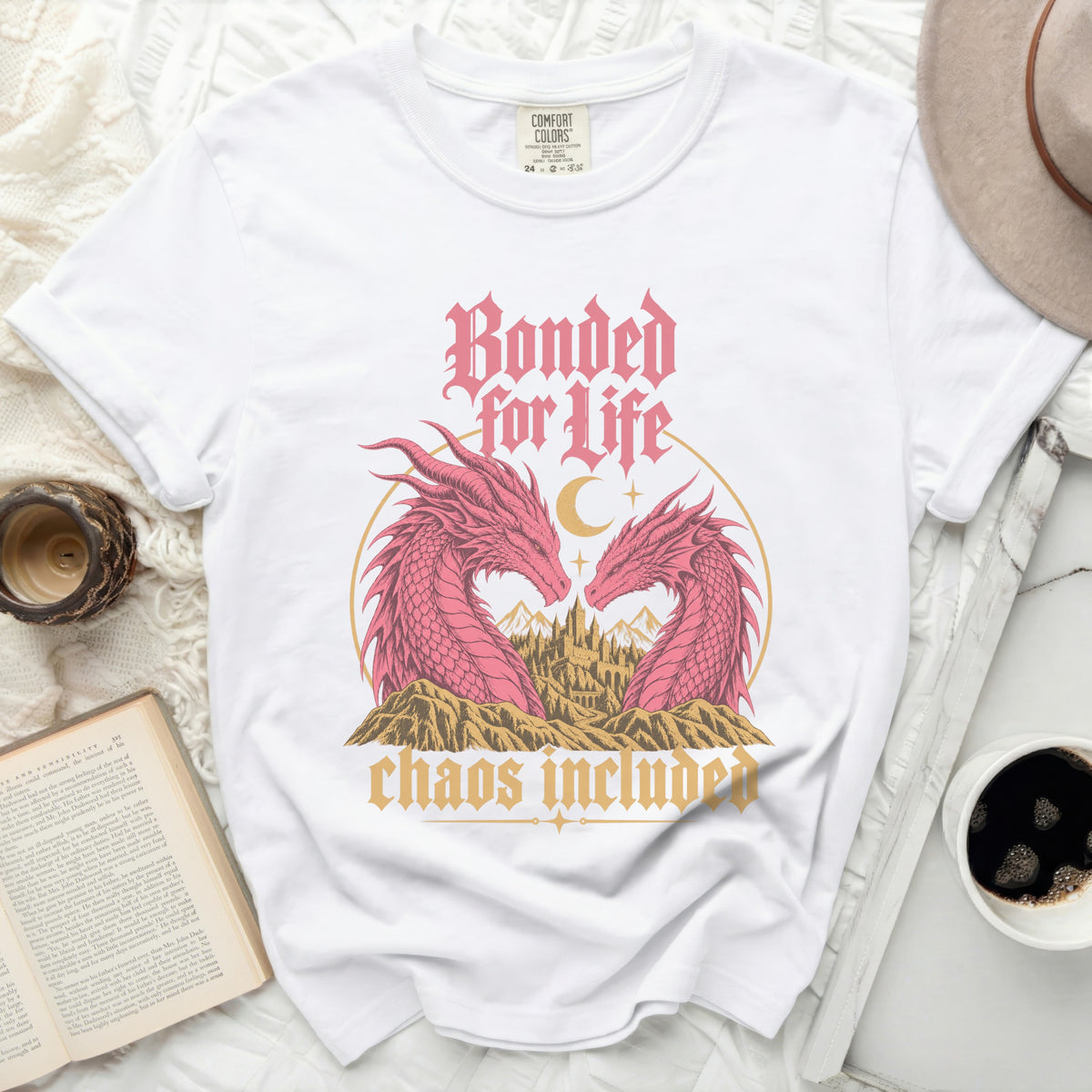 White t-shirt with pink dragons, castle, and text "Bonded for Life, chaos included".