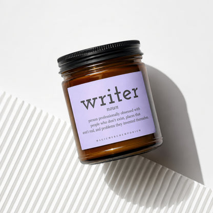 "Writer" definition candle in amber glass jar with black lid.