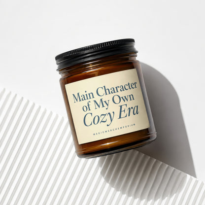 Brown glass candle with label reading "Main Character of My Own Cozy Era".