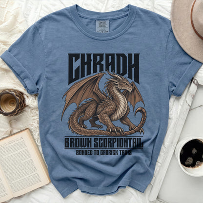 Blue t-shirt with a brown dragon design and text "CHRADH BROWN SCORPIONTAIL BONDED TO GARRICK TAVIS".