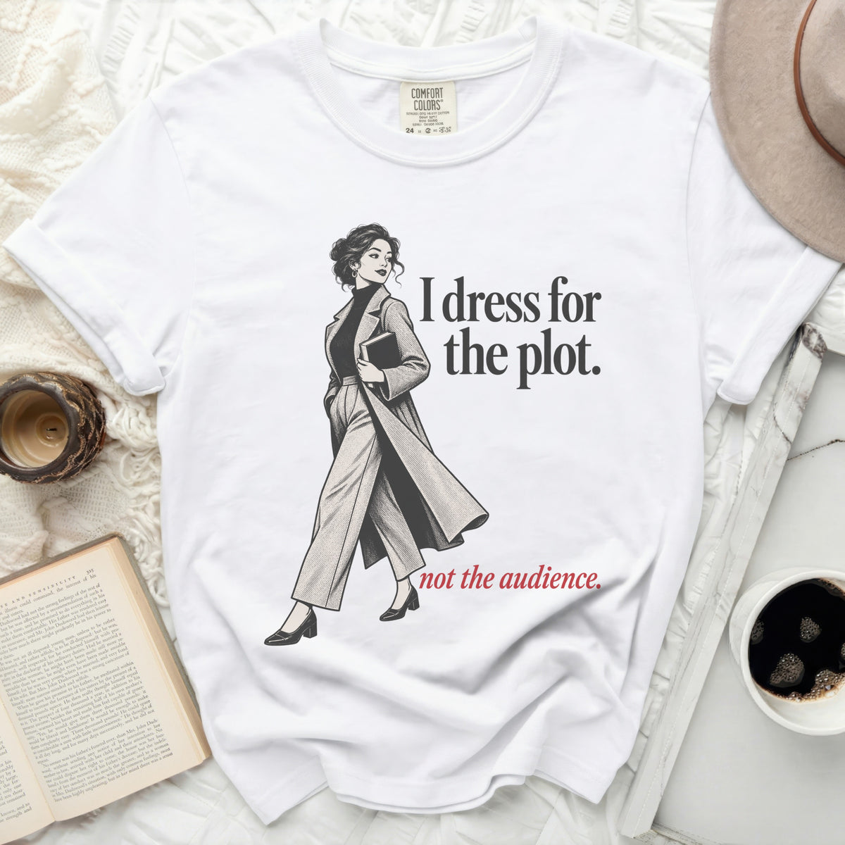 White t-shirt with illustration of a woman and text "I dress for the plot. not the audience."