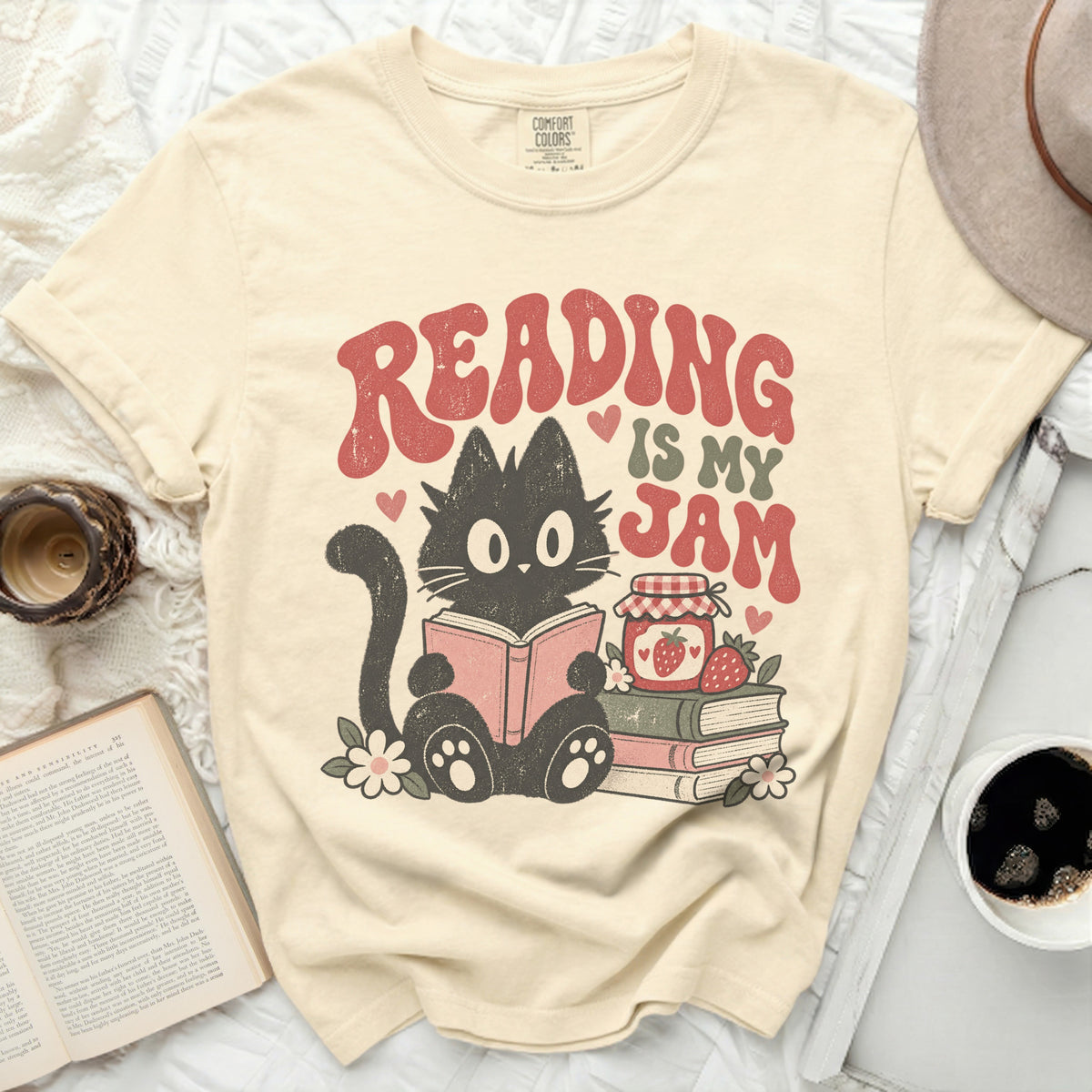 Black cat reading book with "Reading is my Jam" graphic, jam jar, strawberries.