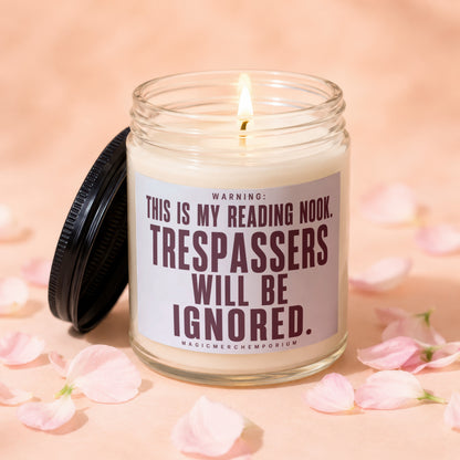 Lit candle in glass jar with lid off, reading "WARNING: THIS IS MY READING NOOK. TRESPASSERS WILL BE IGNORED."