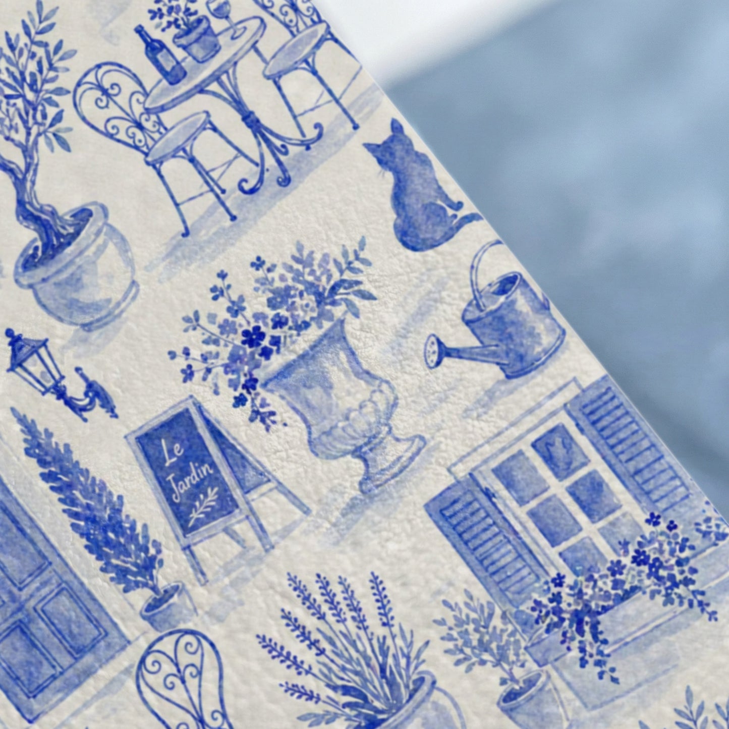 Blue and white watercolor pattern of a French garden scene with a table, cat, and window.