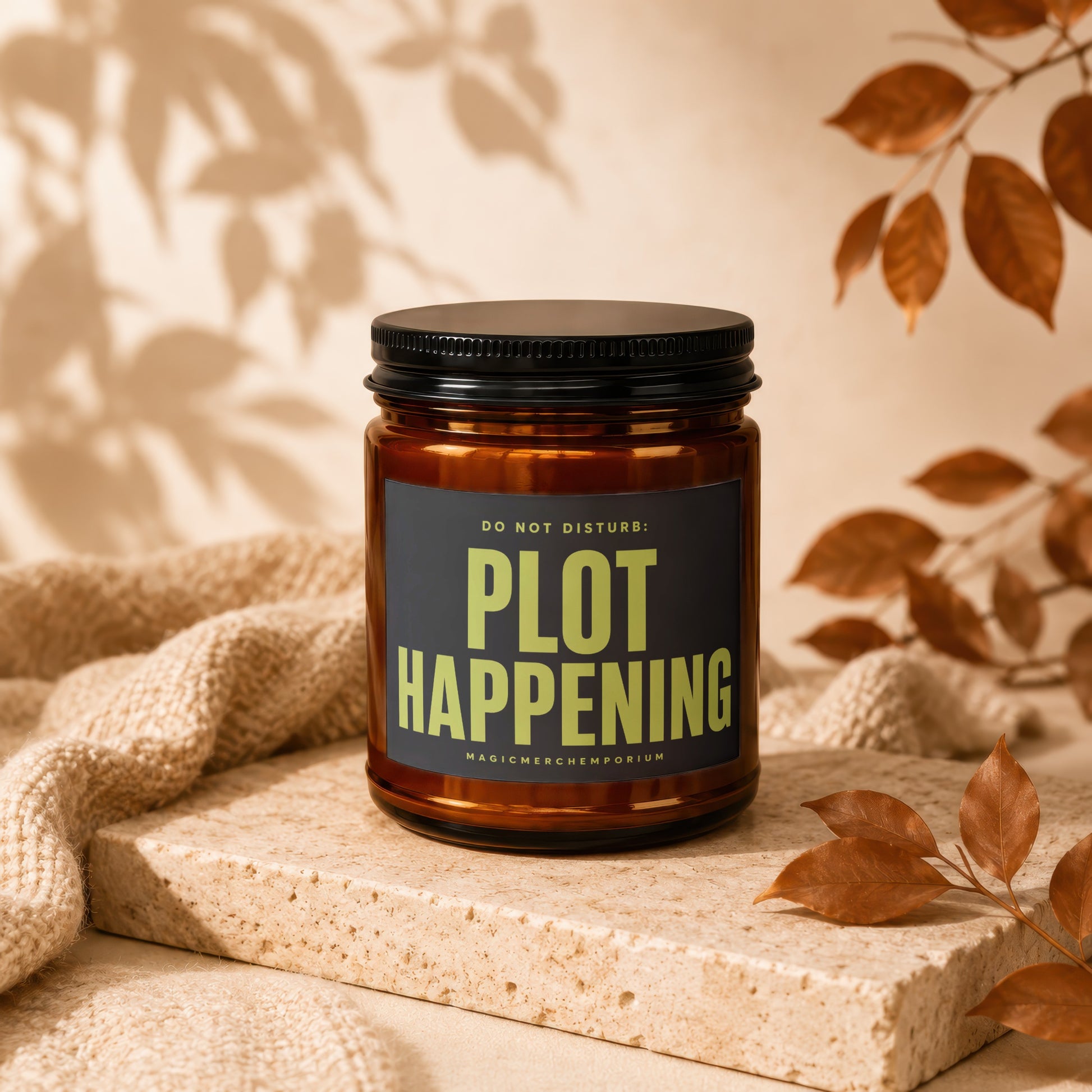 Amber candle with black lid displaying "Plot Happening" text.
