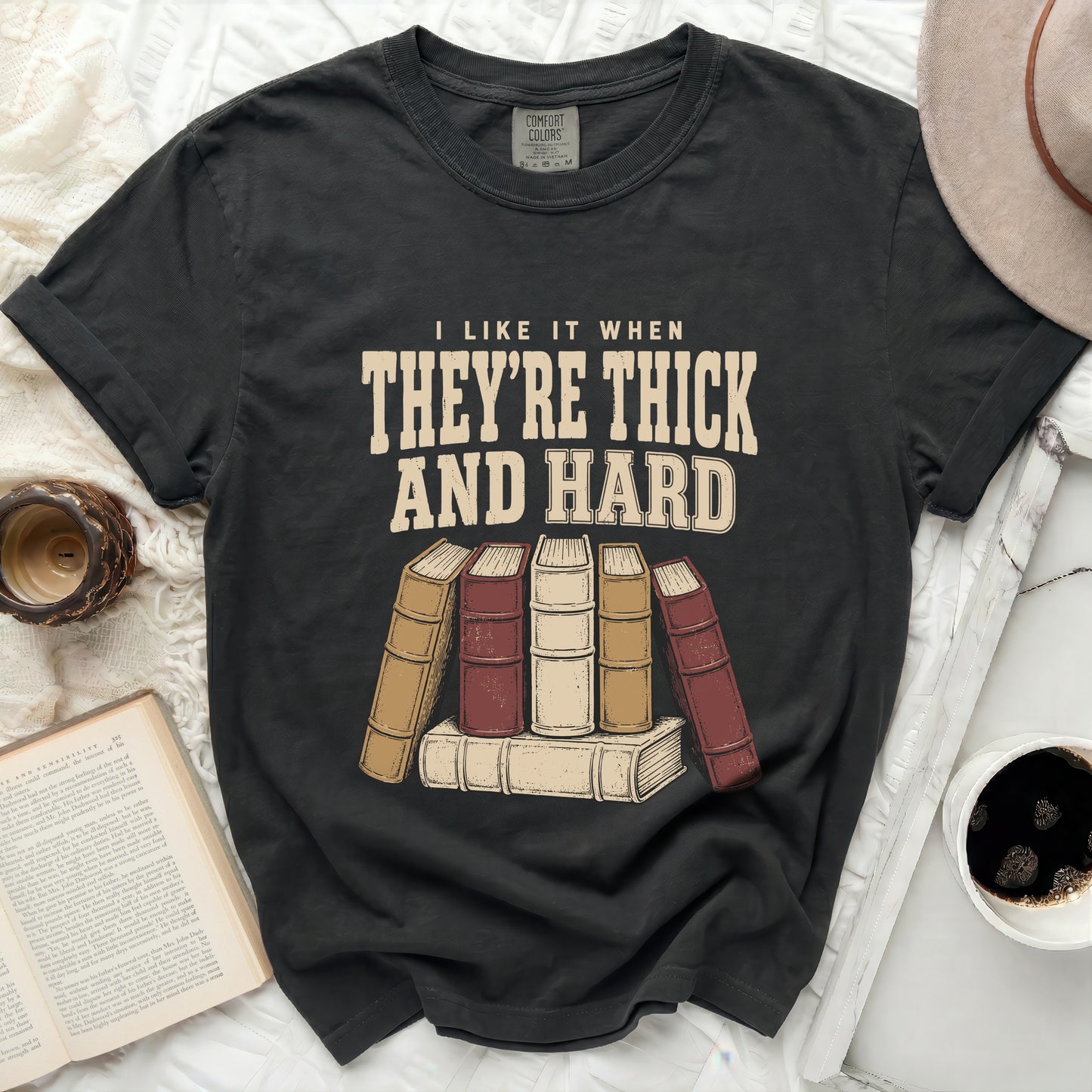T-shirt with "I LIKE IT WHEN THEY'RE THICK AND HARD" and stacked books graphic.