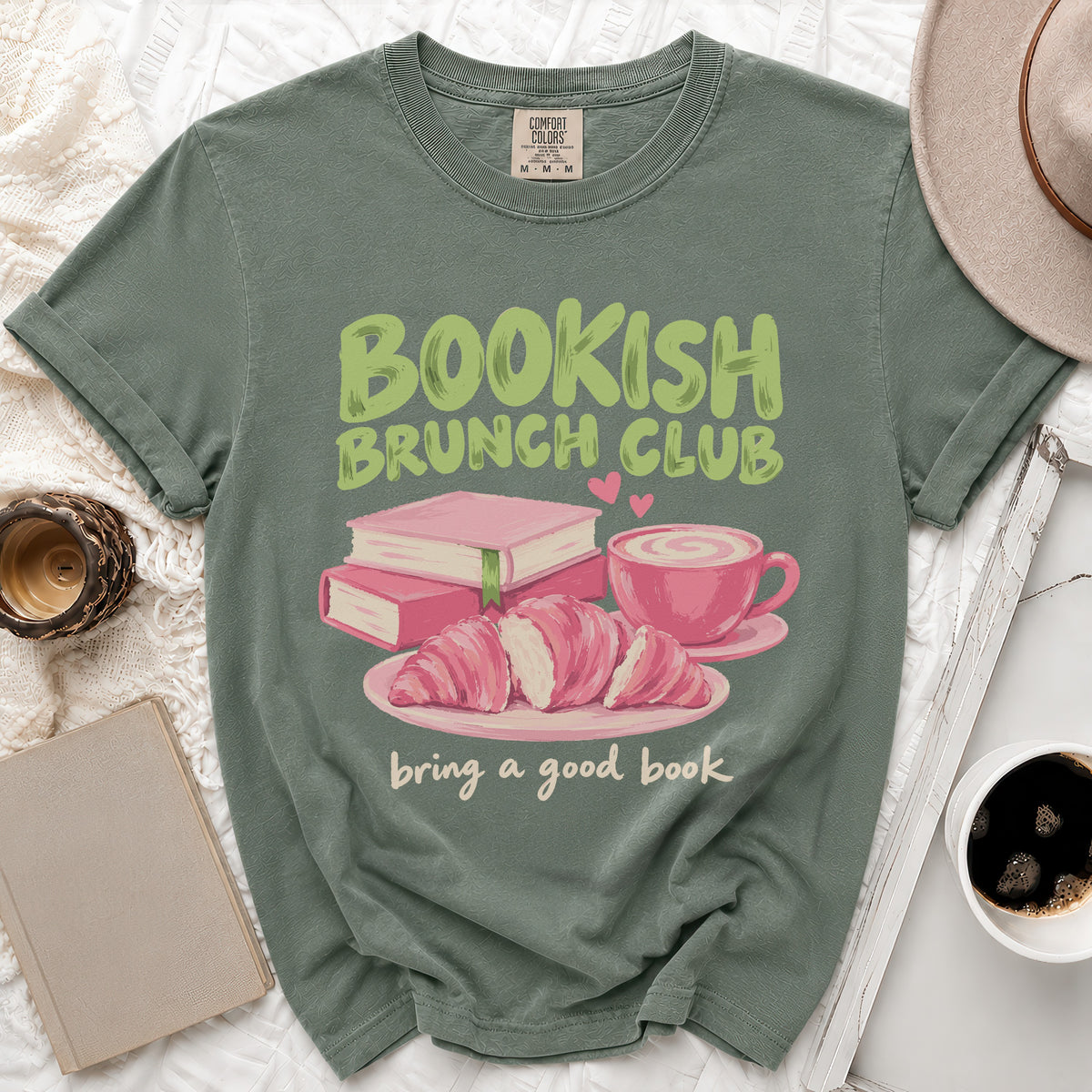 Green t-shirt with "Bookish Brunch Club" and "bring a good book" text, featuring books, croissants, and coffee.