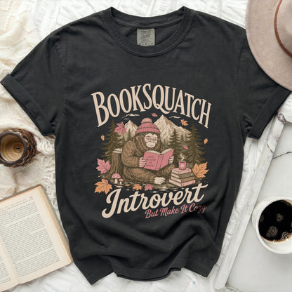 Black t-shirt with a graphic of a reading Bigfoot saying "Booksquatch Introvert But Make It Cozy."