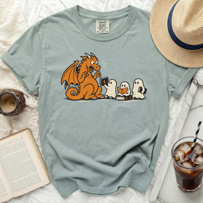 Orange dragon reading a book to three ghosts on a pale blue t-shirt.