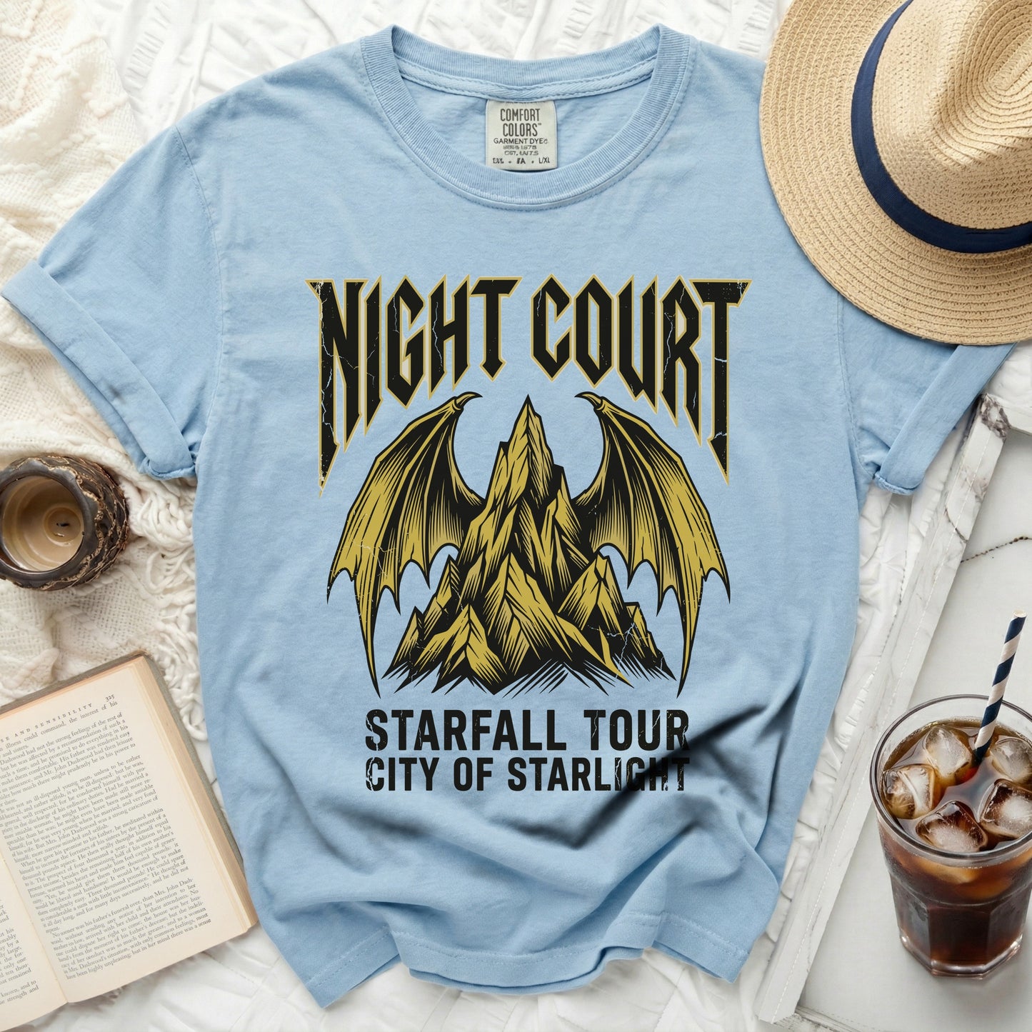 Light blue t-shirt with gold mountain and wings graphic, "Night Court Starfall Tour City of Starlight" text.