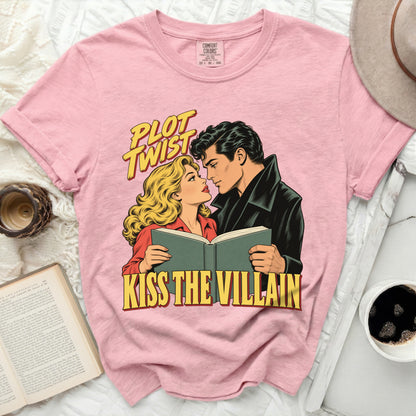 Pink t-shirt with "PLOT TWIST KISS THE VILLAIN" text and comic art of a couple reading.