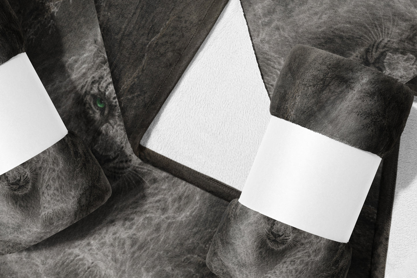 Rolled dark gray throw blanket with lion face print and white blank labels.