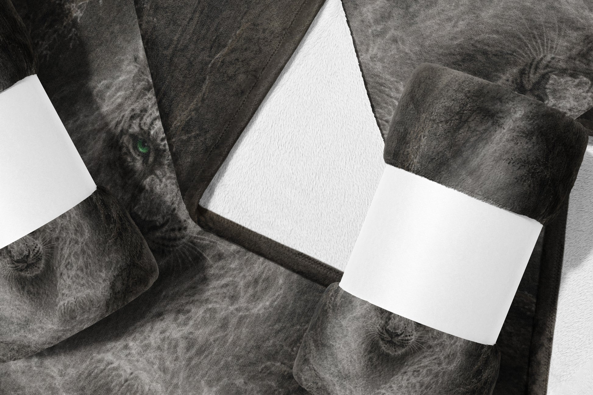 Rolled dark gray throw blanket with lion face print and white blank labels.