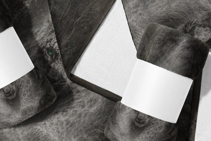 Rolled dark gray throw blanket with lion face print and white blank labels.