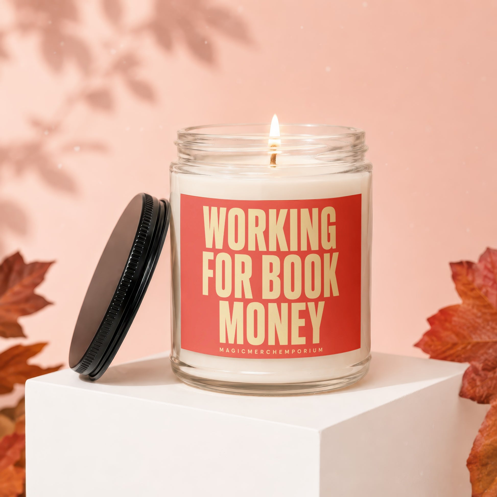 Burning candle with "WORKING FOR BOOK MONEY" text on a red label on a pink background.
