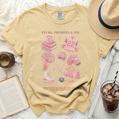 Yellow t-shirt with pink graphics of hockey gear, books, and mugs, featuring text.