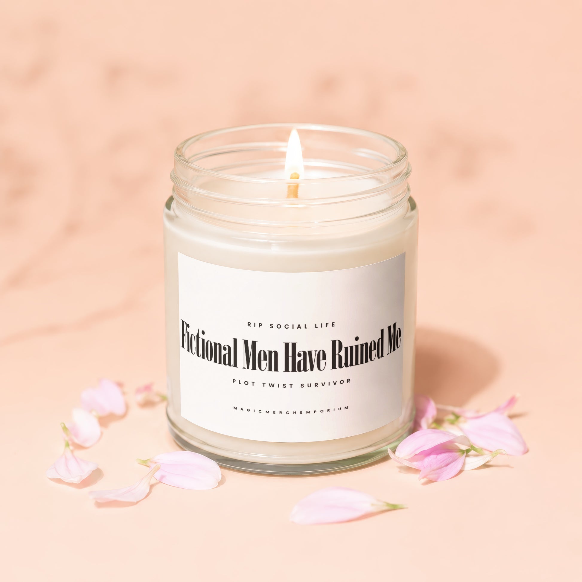 Lit candle in glass jar with label "Fictional Men Have Ruined Me" surrounded by petals.