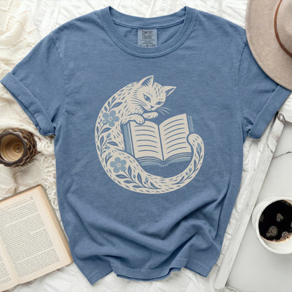 Blue t-shirt with a cream graphic of a cat reading a book.