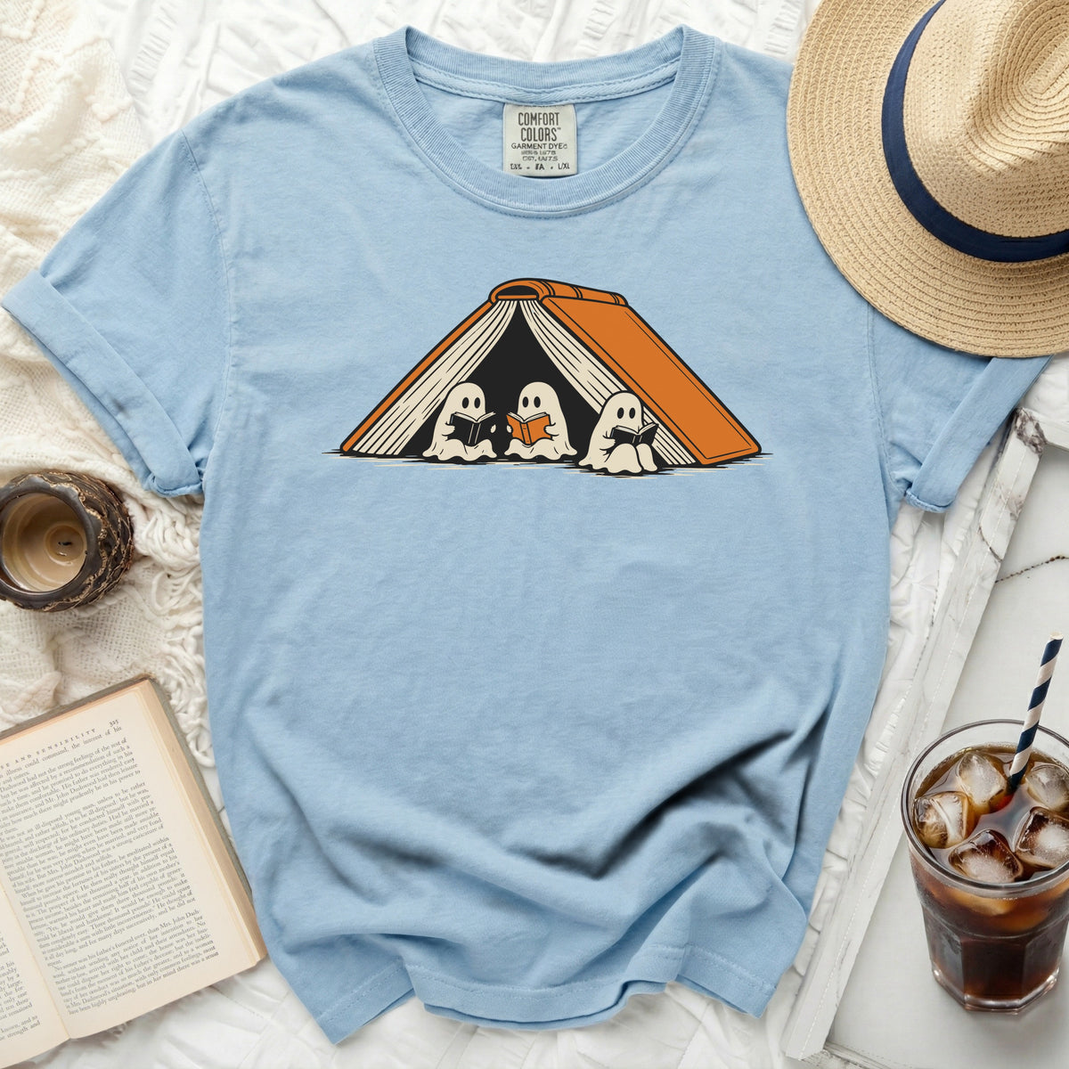 Light blue t-shirt with three ghosts reading books inside an open orange book.