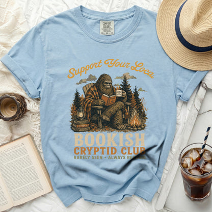 Comfort Colors light blue t-shirt with Bigfoot reading and "Bookish Cryptid Club" graphic.