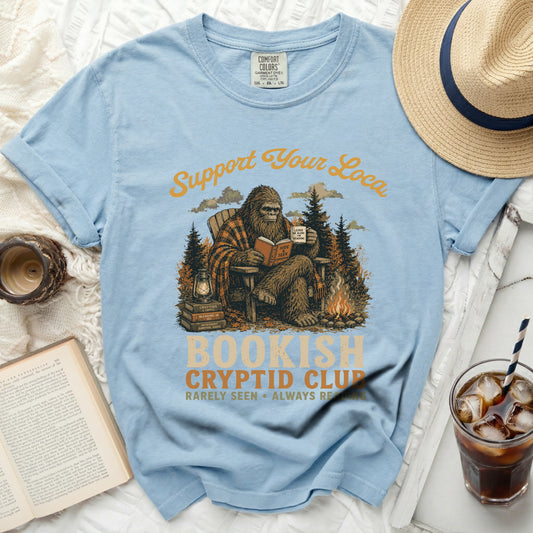 Comfort Colors light blue t-shirt with Bigfoot reading and "Bookish Cryptid Club" graphic.