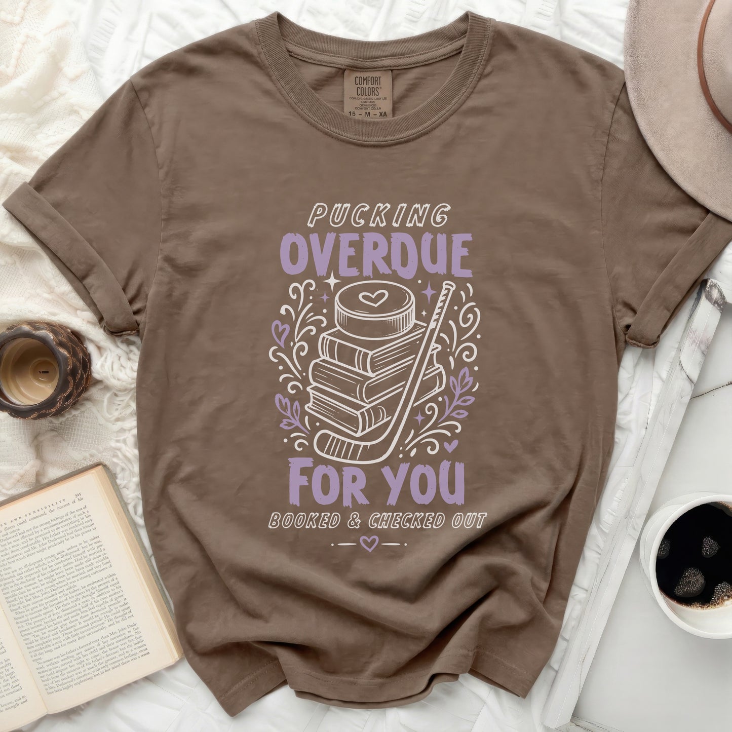 Brown t-shirt with "Pucking Overdue Booked & Checked Out" text and hockey imagery.