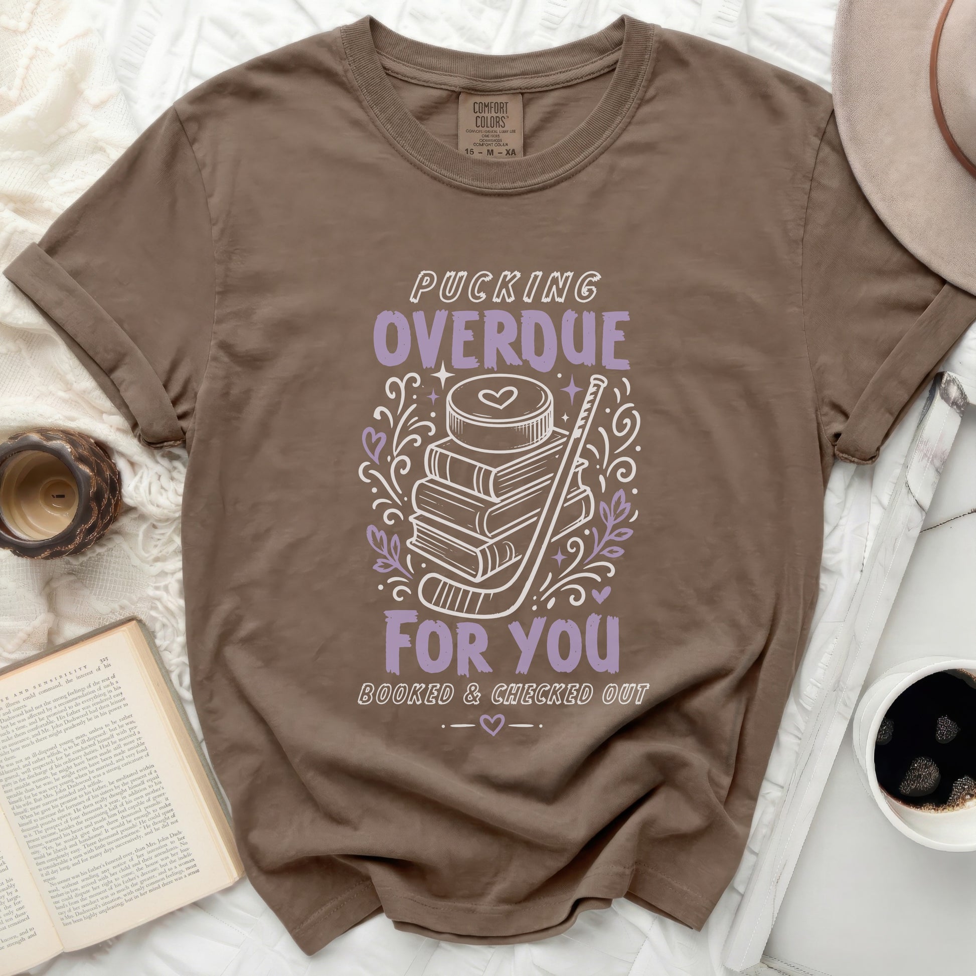 Brown t-shirt with "Pucking Overdue Booked & Checked Out" text and hockey imagery.