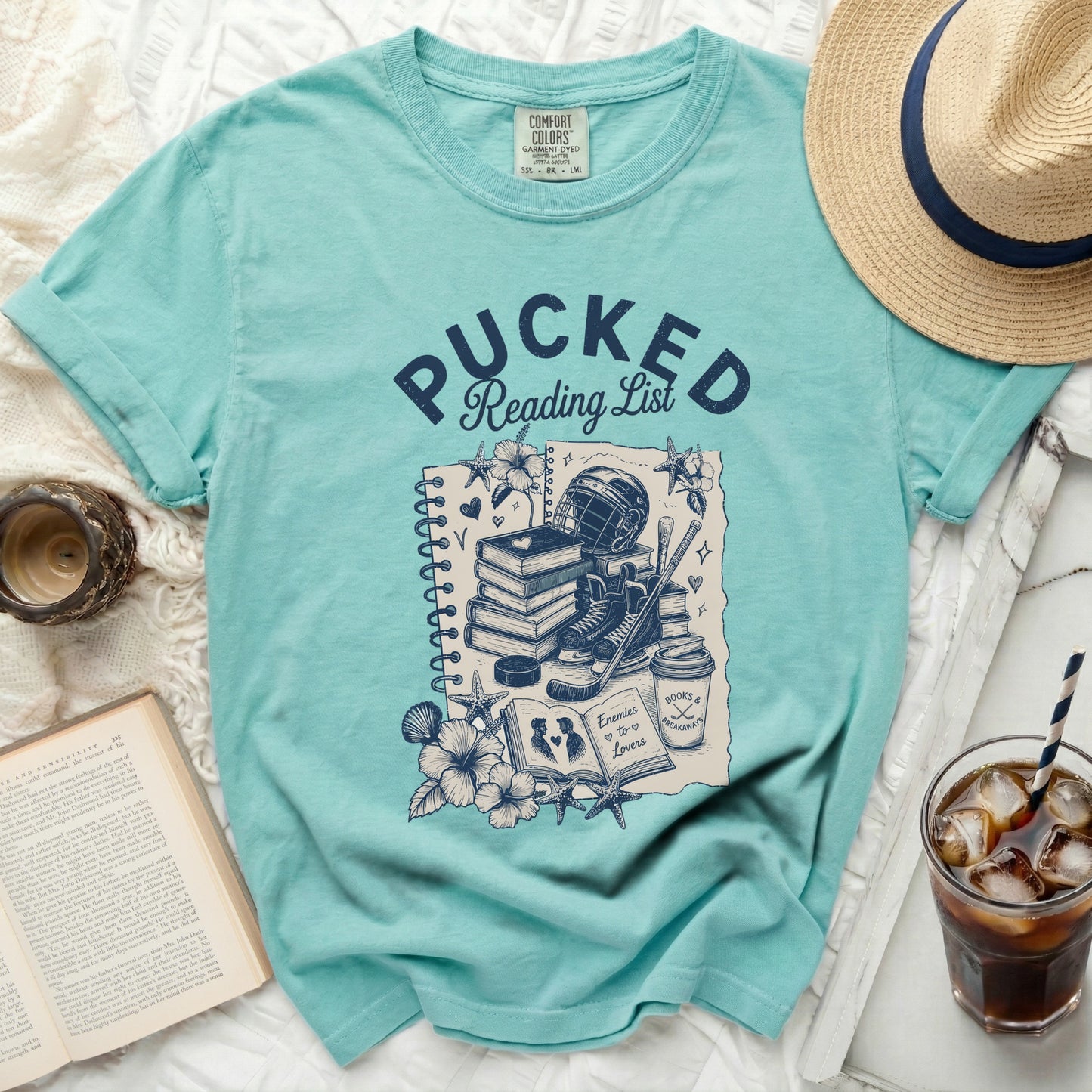 Teal t-shirt with "Pucked Reading List" graphic and hockey elements.