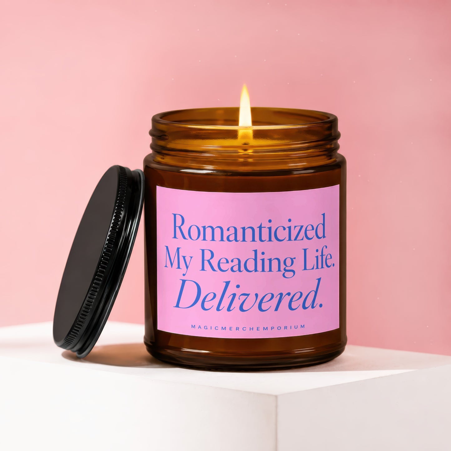Lit candle in amber jar with pink label that reads "Romanticized My Reading Life. Delivered."