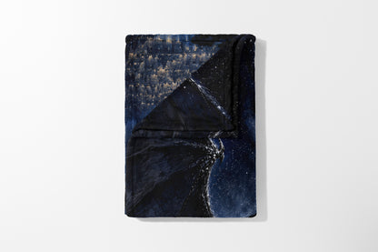Folded blanket with a dark blue and gold starry night sky pattern.
