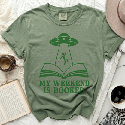 Green t-shirt with UFO abducting a person from an open book.