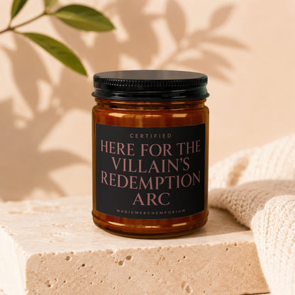 Amber jar candle with black lid and label stating "Certified Here for the Villain's Redemption Arc."