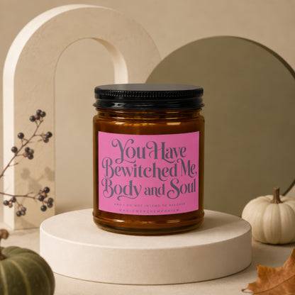 Amber jar candle with pink label reading "You Have Bewitched Me, Body and Soul."