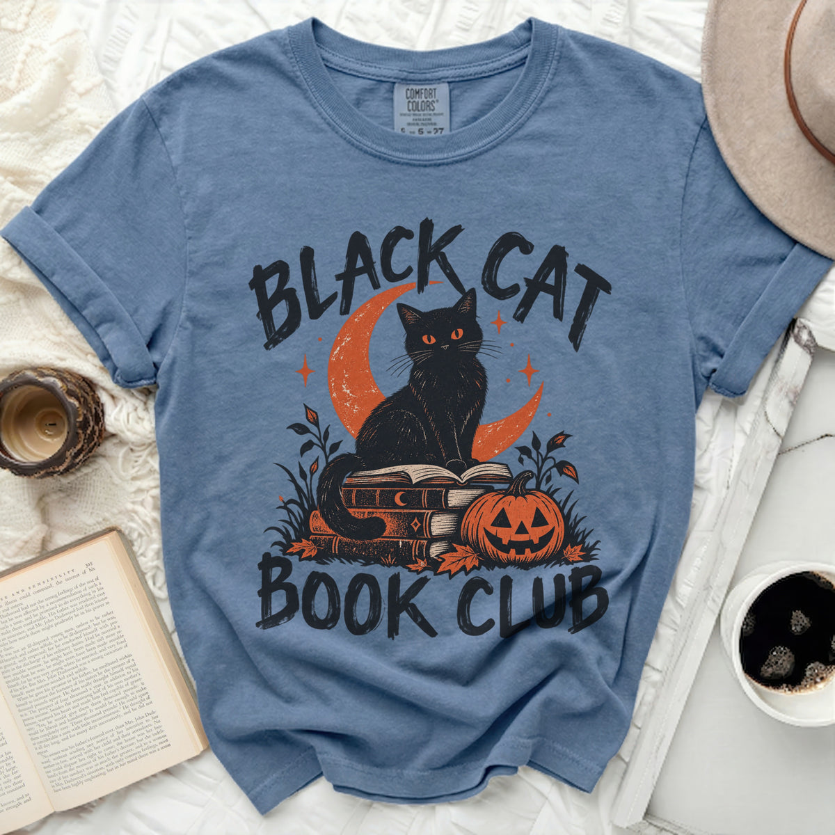 Black cat with orange eyes sits on books next to pumpkin with "Black Cat Book Club" text.