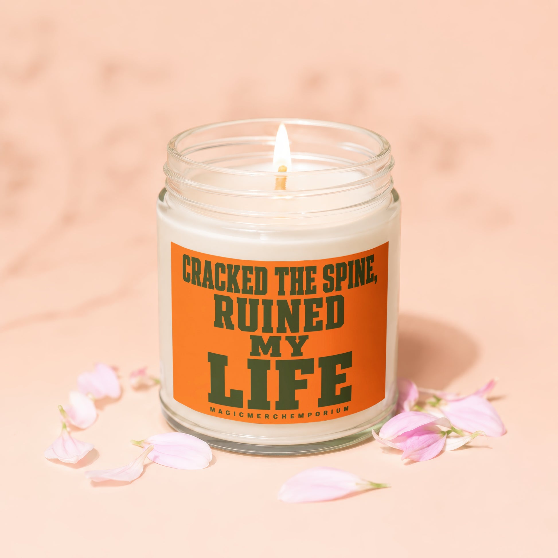 Candle with text "Cracked the spine, ruined my life" and "MagicMerchEmporium".