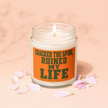 Candle with text "Cracked the spine, ruined my life" and "MagicMerchEmporium".