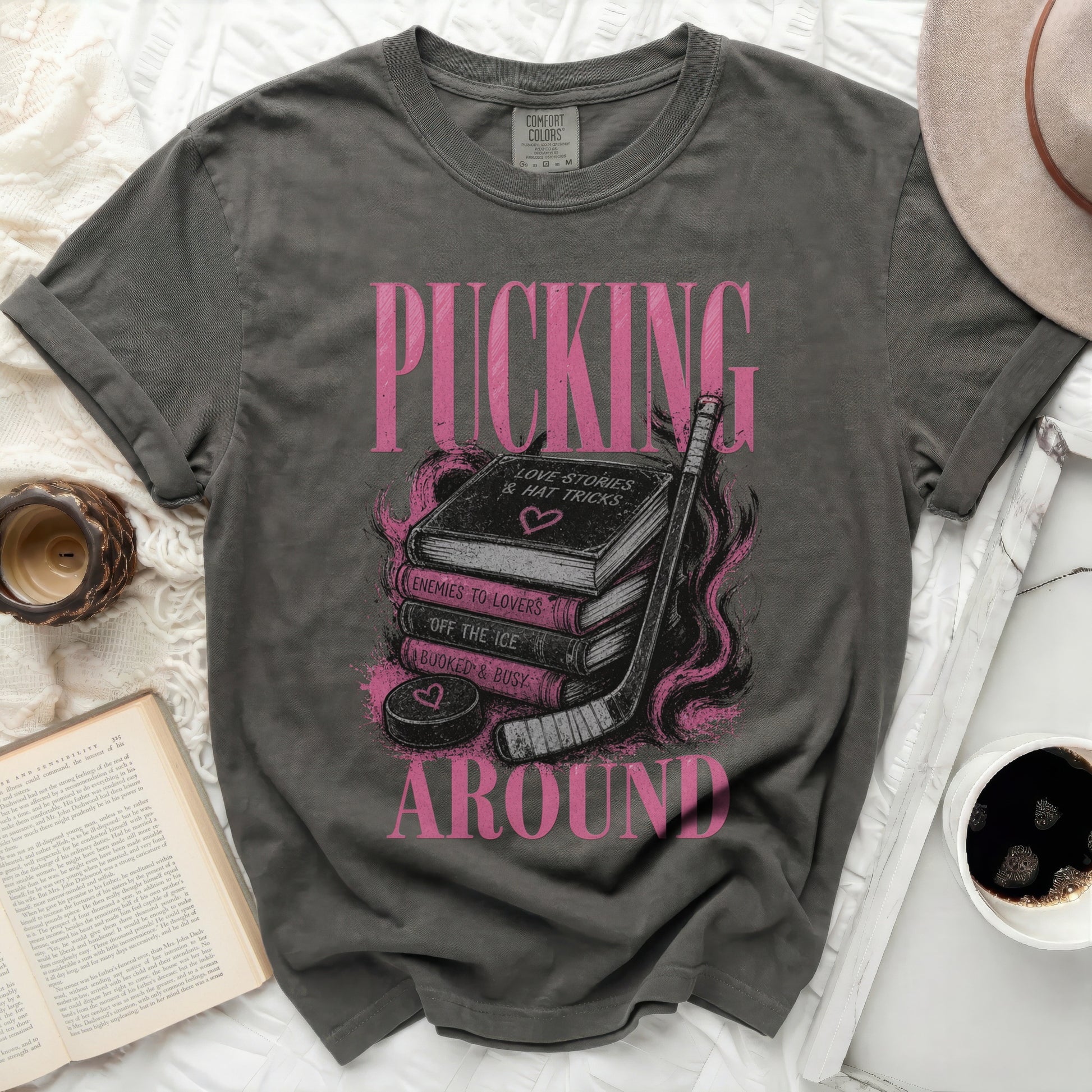 Dark grey t-shirt with "PUCKING" text and stack of books with hockey puck.