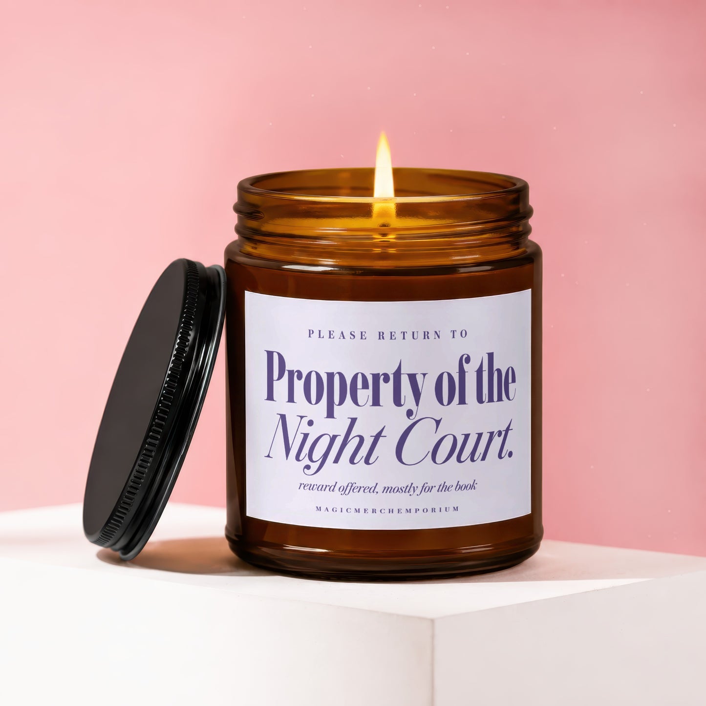 Amber glass candle with lit wick, lid beside it, reads Property of the Night Court.