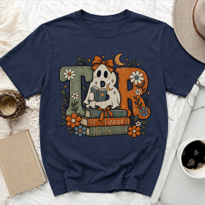 Ghost reading book on stack of books with floral and celestial design on navy t-shirt.