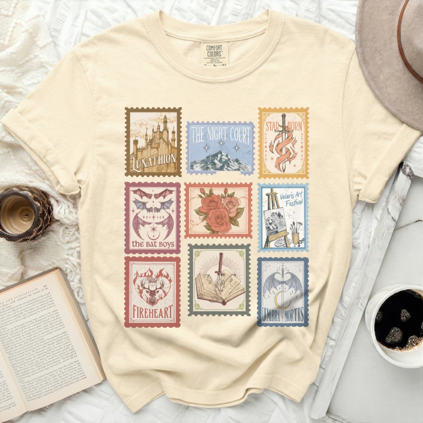Cream t-shirt with nine illustrated stamps featuring fantasy titles and motifs.