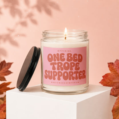 Glass candle with pink label saying "OFFICIAL ONE BED TROPE SUPPORTER".