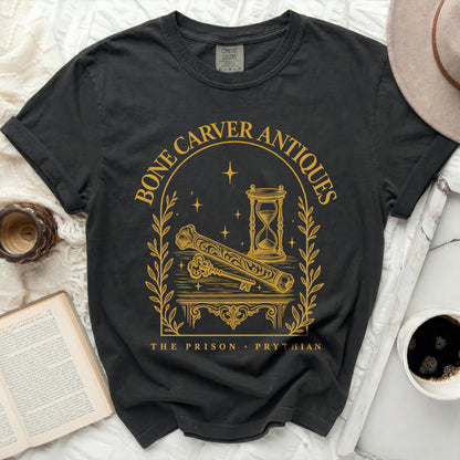 Charcoal black t-shirt featuring a gold print with an arch, hourglass, key, bone, and text.